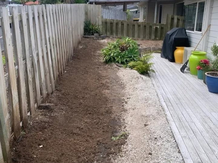 After: the same fence line with the stumps gone and the ground raked level beside the deck